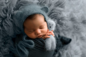 Newborn Photographer, Sleeping Baby holding blue teddy bear in blankets