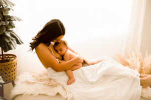 Motherhood Photography, Mother laying on bed while holding baby breastfeeding