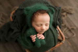 Newborn Photographer, Sleeping newborn comfy in basket wrapped in green blanket