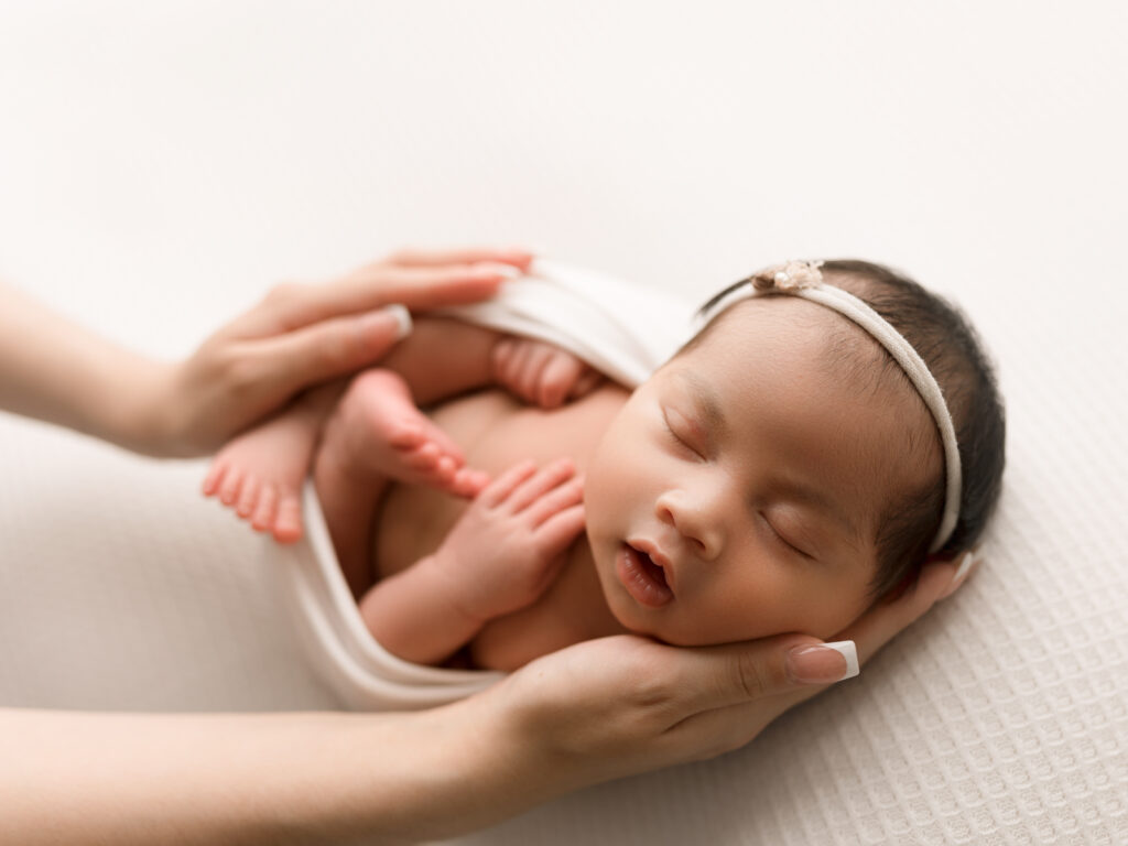 Newborn Photographer, a mother's hands hold a sleeping newborn baby