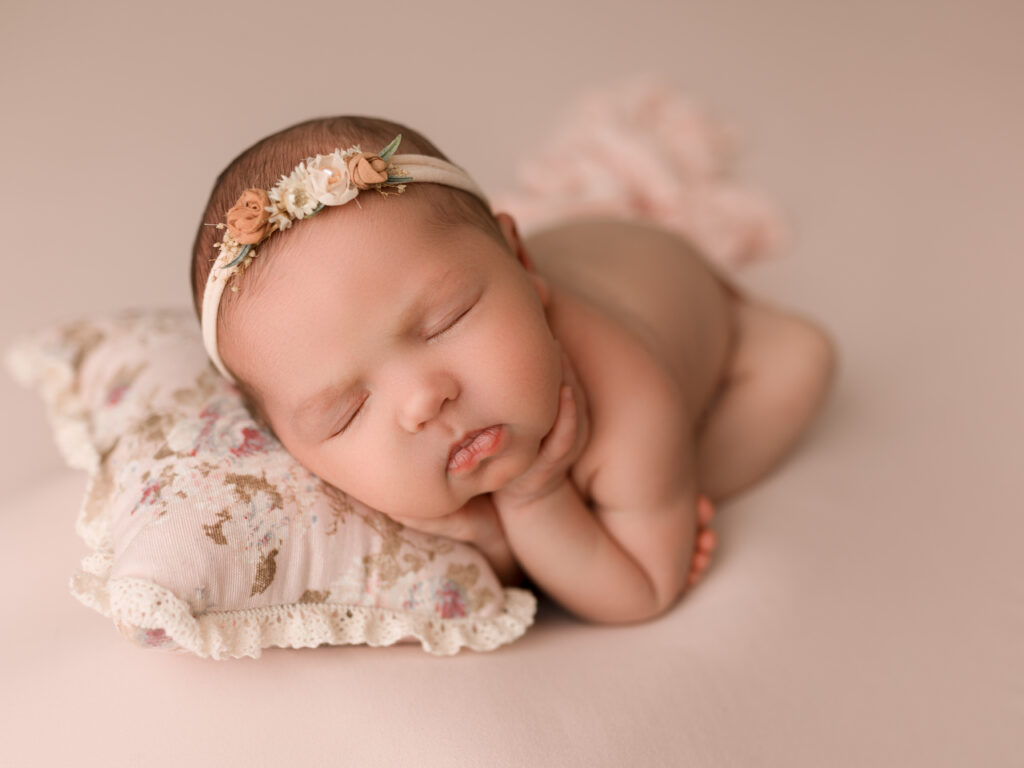 Newborn Photographer, Sleeping Baby is cuddled on floral pillow