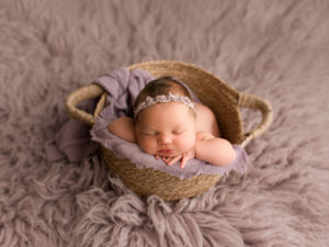 Newborn Photographer, a baby sleeps in a basket on a shag rug